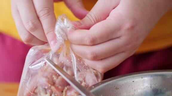 孩子的手在家里把肉装在塑料袋里