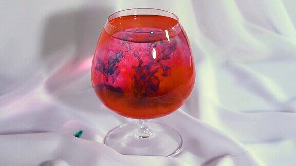 在玻璃杯里把蓝色颜料和红色的水混合颜料和水的混合物