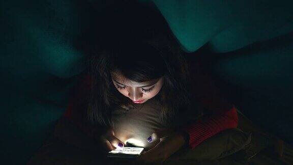 晚上躺在床上看手机或与人聊天的年轻女孩或青少年