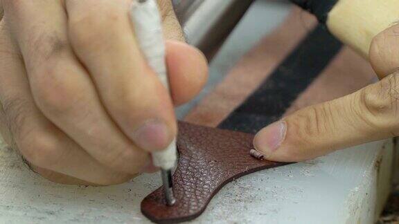 本厂生产概念皮包用锤子和打孔器在皮带上打孔