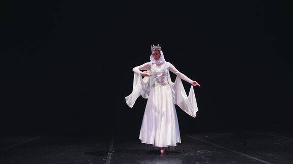 芭蕾舞演员走上舞台一位芭蕾舞演员穿着美丽的白色长袍在黑色背景上跳舞Raymonda变异