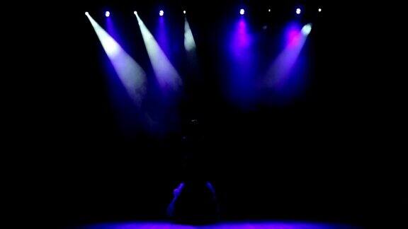 美丽的歌手在舞台上与蓝色的光