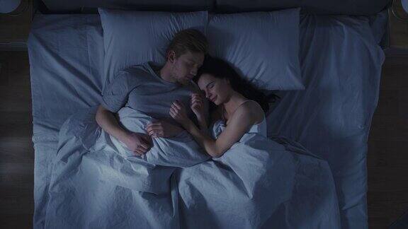 年轻夫妇拥抱在床上睡觉