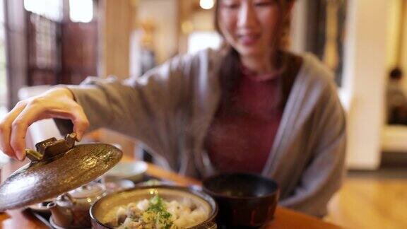 在日本餐馆里一名年轻女子拿着一个陶罐的盖子