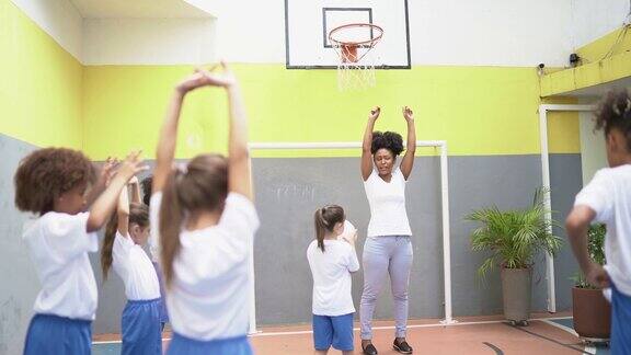 体育活动老师在学校和学生们一起伸展手臂