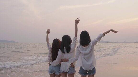 微笑快乐的亚洲朋友群年轻的女人一起在海边的海滩夏季度假日落剪影黄昏假日旅游享受生活周末活动人们的生活方式慢镜头4K电影