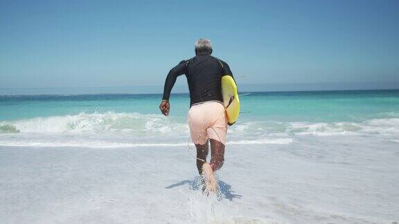 老人拿着冲浪板跑向大海