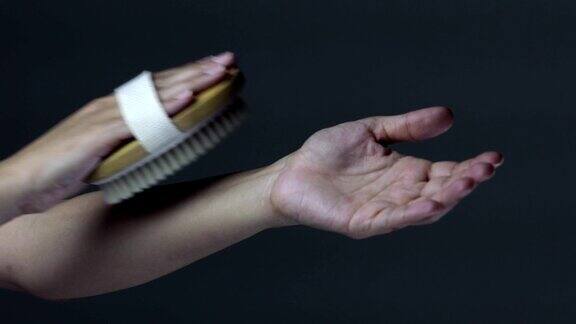 一位妇女用刷子擦干手臂上的死皮