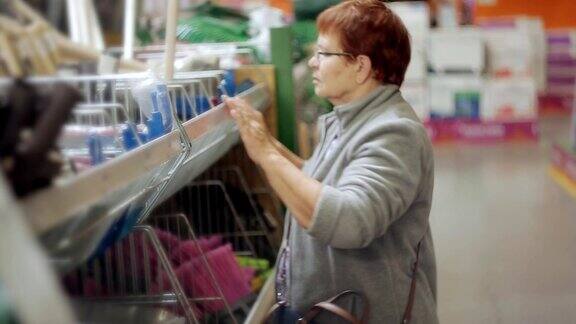 一位上了年纪的妇女在一家大型超市的工具处为花园挑选必要的设备