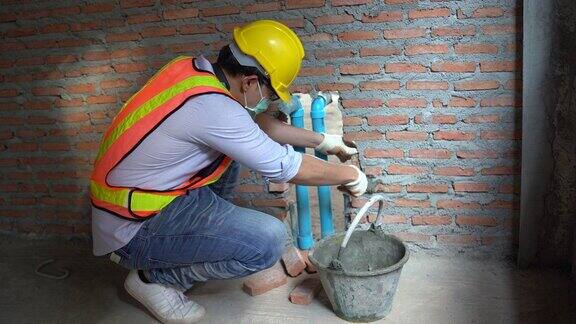 亚洲砌砖工人正在安装砌砖为新建筑居民的水管系统关闭pvc管