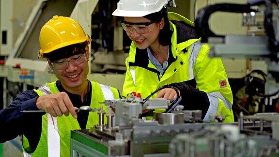 两位男和女机械工程师在一个重工业制造工厂建造机器人机械