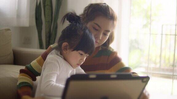 年轻的母亲和女儿在家里用平板电脑做作业