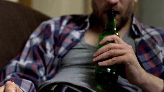 醉鬼大胡子坐在沙发上喝啤酒上瘾下视