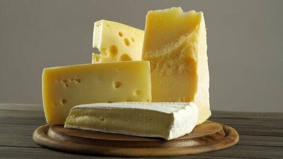 不同种类的奶酪法国布里干酪瑞士奶酪意大利帕尔马干酪一组奶酪切片放在圆形木砧板上