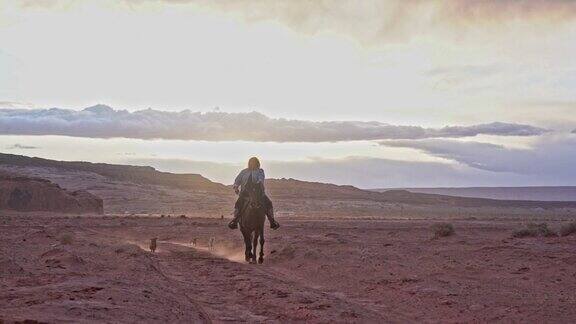 一个年轻的纳瓦霍妇女骑着马飞奔过纪念碑谷附近的沙漠