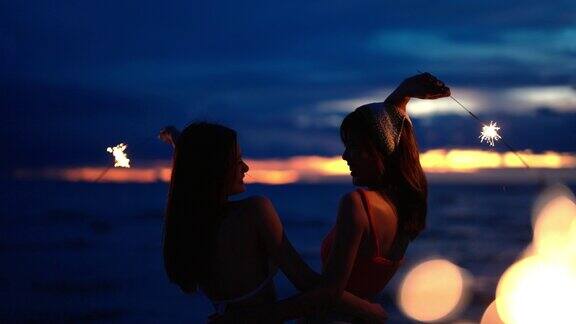 4K亚洲女性朋友在夏夜的热带海岛海滩上一起玩烟火