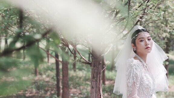 这位年轻的东亚新娘身穿白色婚纱在公园里拍婚纱照