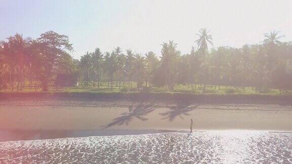 穿着礼服的女人走在阳光明媚的巴厘岛梦幻般的沙滩上