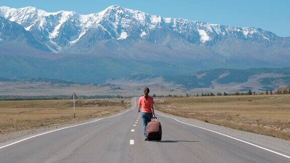 带着行李箱在山路上旅行的女人