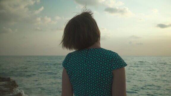 一个成年女子走在热带海岸上在日落
