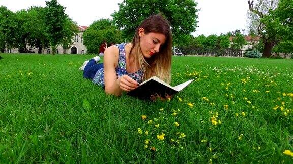 美丽的女学生在校园草地上读书