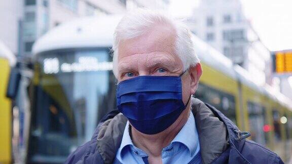 在电车站戴防护口罩的老人