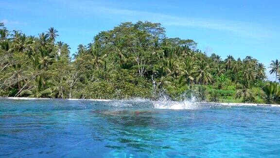 特写:女孩在巴厘岛豪华丛林度假村的无限泳池中跳跃和跳水