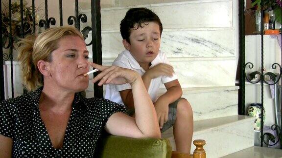 小男孩一边抽烟一边看着妈妈