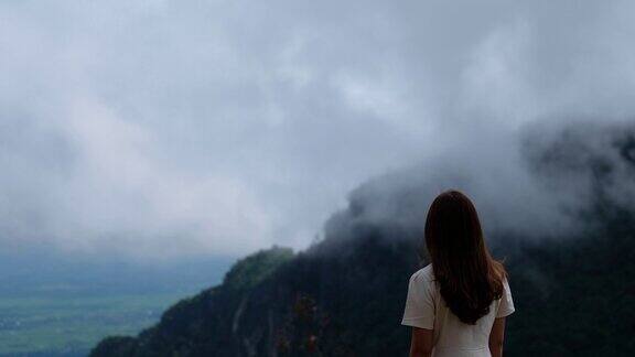 一个女旅行者在看一个美丽的雾蒙蒙的山景
