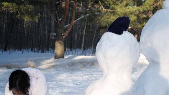 黑色皮肤的女孩在森林里堆雪人玩