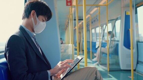 商人戴着医用口罩在公共交通工具上玩平板电脑