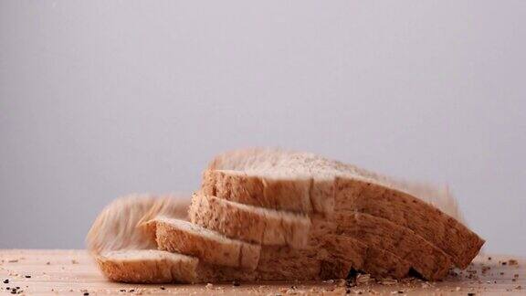 关闭全麦杂粮面包片落在木制桌子上的白色背景慢动作面包片食品片健康食品理念