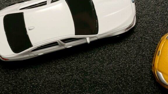 俯视图:车祸-玩具模型汽车碰撞白色玩具汽车的特写(慢镜头)