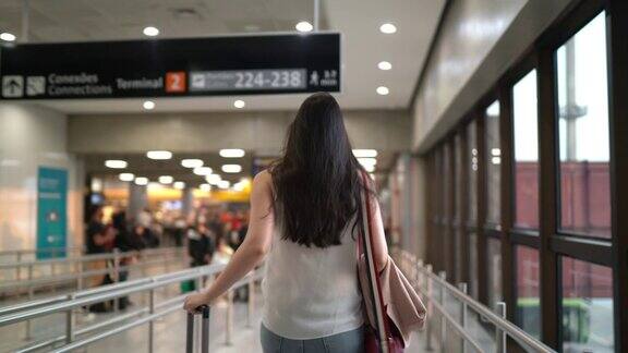 年轻的女旅行者在机场走着戴着口罩