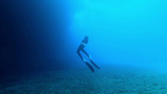 一名潜水员在海底附近游泳的慢动作水下镜头