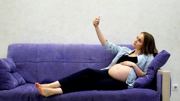 美丽孕妇坐在客厅沙发上自拍社交网络