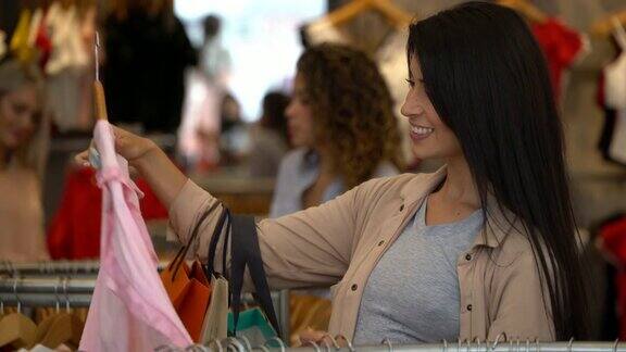 美丽的拉丁美洲妇女看着一件衬衫在衣架上微笑
