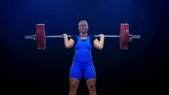 女子举重运动员身穿蓝色运动服在比赛中进行挺举