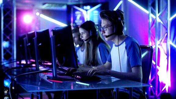 职业电竞玩家团队在网络游戏锦标赛上玩电子游戏女孩和男孩戴上耳机舞台被霓虹灯照亮