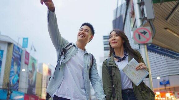 亚洲活跃的年轻夫妇在晚上的城市蜜月旅行有吸引力的新婚夫妇背包客游客走在街上享受在情人节假期花时间约会在一起