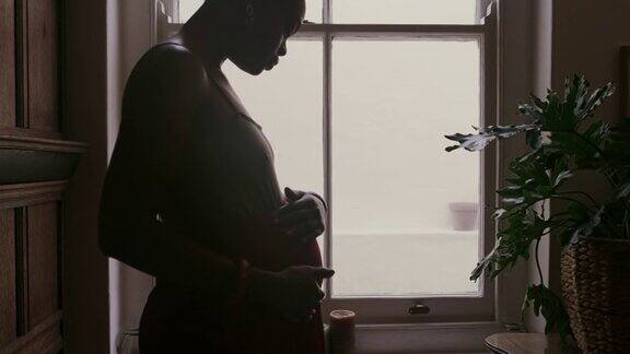 一段4k视频记录了一名怀孕女性在家摸肚子和看窗外的情景