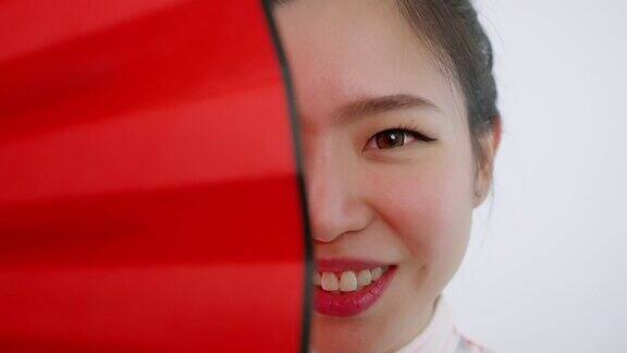 中国亚洲美女春节脸的特写红色扇子遮住了她的右半边脸微笑着看着镜头