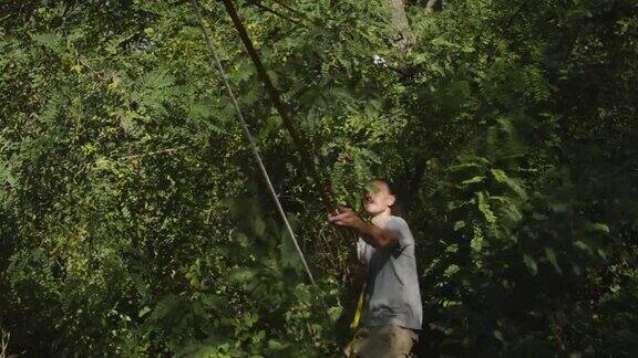 一名白人男子在河上的树木之间架设绳索设备夏天黎明时分一个人在水上练习高空吊索