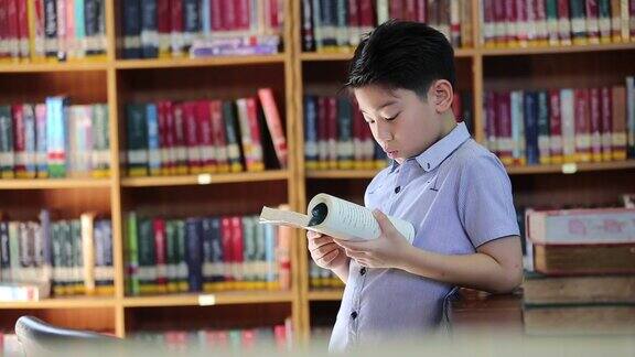 一个亚洲小男孩厌倦了阅读在泰国的图书馆