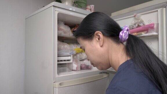 女人把冷冻食品放在冰箱的冰柜里