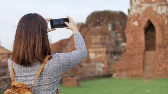 一名女游客在泰国大城府历史公园用手机拍照