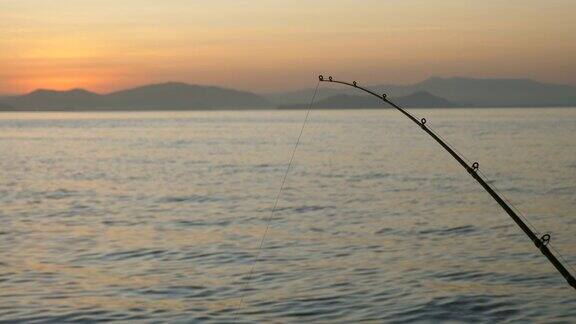 日出时在海洋上钓鱼竿