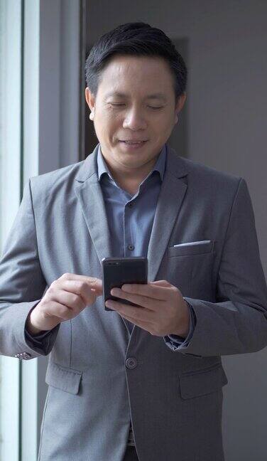 41岁的亚洲商人使用智能手机浏览社交媒体输入信息查看新闻或玩手机游戏技术