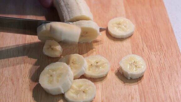 在木板上切香蕉特写切香蕉在切板上用刀切香蕉的人