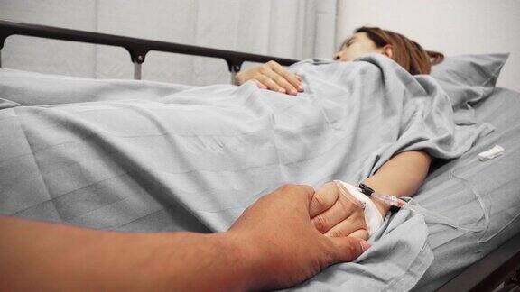 亚洲病人在床上握着家人的手